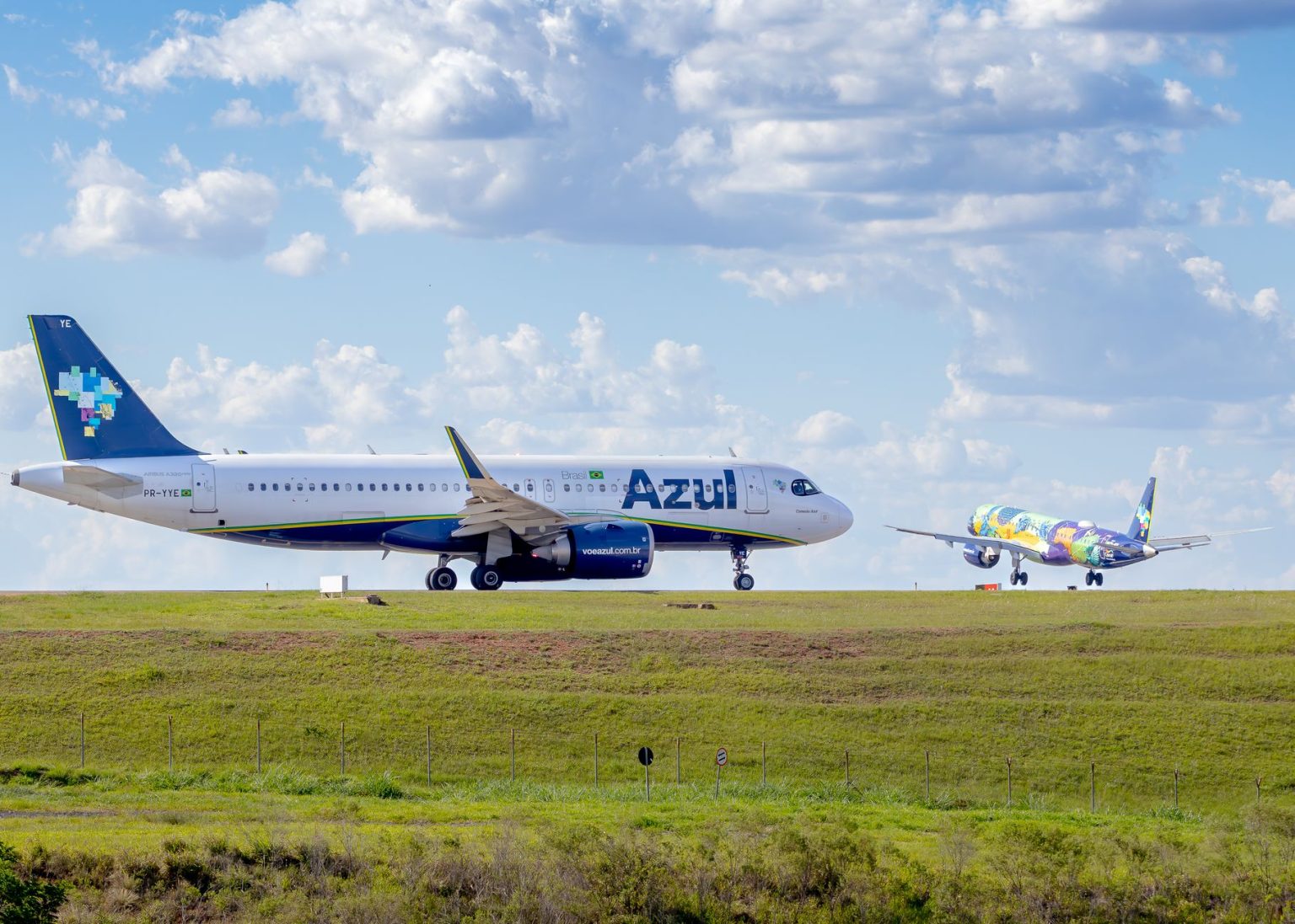 Aeronaves da Azul posicionadas em um aeroporto sob céu azul.